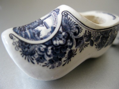 A white porcelain souvenir clog painted in Delft Blue with a windmill scene